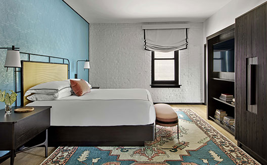 The Fiddle Suite at Hotel Fontenot image shows a plush king bed and a settee with a desk and chair